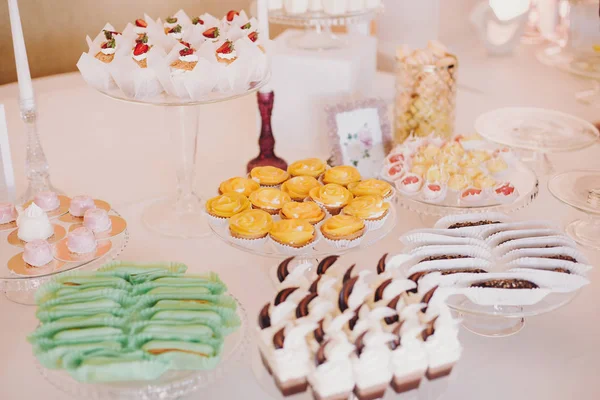 おいしいエクレア マカロン カップケーキ デザート テーブルの上のお菓子は 結婚披露宴でパーティーします 白とピンクのスタイリッシュなお菓子のバー クリスマスと新年のごちそう お祝い事やパーティー — ストック写真