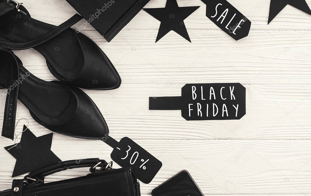 Black Friday big sale text on price tag sign, minimalistic flat lay. Special discount christmas offer. Stylish advertising message at black gift boxes on white rustic background. Christmas shopping