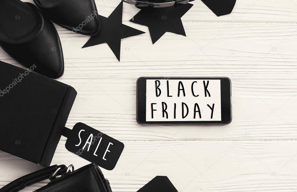 Black Friday big sale text on phone screen. Special discount christmas offer. Phone with advertising message at gift boxes and price tags. Stylish minimalistic flat lay. Shopping time
