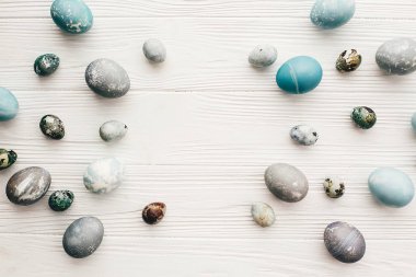 Mutlu Paskalyalar. Düz şık Paskalya yumurtaları metin için yer ile beyaz ahşap zemin üzerinde yatıyordu. Paskalya yumurta modern çerçeve mavi ve gri renkli doğal boya ile boyanmış. Tebrik kartı mockup