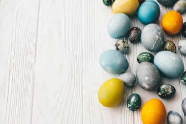 Metin için yer ile beyaz ahşap zemin üzerinde şık Paskalya yumurta. Modern Paskalya yumurtaları mavi, gri, sarı mermer renkli doğal boya ile boyanmış. Mutlu Paskalya desen, tebrik kartı