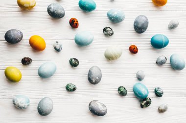 Mutlu Paskalya desen. Şık Paskalya yumurta beyaz ahşap zemin üzerinde düz yatıyordu. Modern Paskalya yumurtaları mavi, gri, sarı mermer renkli doğal boya ile boyanmış. Tebrik kartı