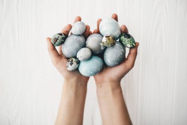 Beyaz ahşap zemin üzerinde eller şık Paskalya yumurta. Modern Paskalya yumurtaları holding eller gri ve mavi mermer renkli doğal boya ile boyanmış. Mutlu Paskalya