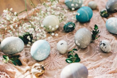 Şık Paskalya yumurtası güneşli ışık ahşap rustik kumaş üzerine bahar çiçekleri ile. Modern Paskalya yumurtaları mavi, gri mermer renkli doğal boya ile boyanmış. Mutlu Paskalyalar, tebrik kartı