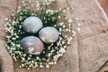 Mutlu Paskalyalar. Şık Paskalya yumurta yuvada ahşap, en iyi görünümü üzerinde rustik kumaş üzerine bahar çiçek. Modern Paskalya yumurtaları gri mermer renkli doğal boya ile boyanmış. Tebrik kartı