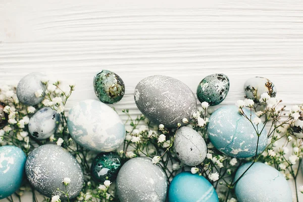 时尚的复活节彩蛋与春天的花朵在白色木制的背景与空间为文本 平放置 用蓝色和灰色的天然染料涂成的现代复活节彩蛋 复活节快乐 — 图库照片