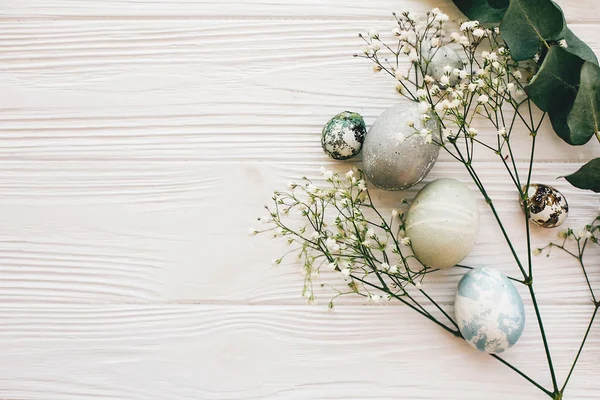 Стильные Пасхальные Яйца Весенними Цветами Зеленой Ветвью Белом Деревянном Фоне — стоковое фото
