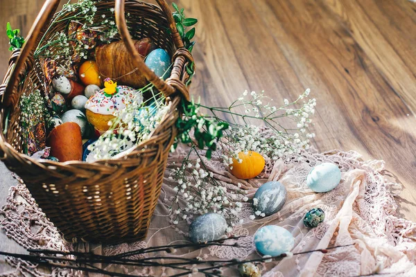イースター バスケット卵 イースターのパン ソーセージ 花と素朴な木製の背景の上に布枝とバター 幸せなイースターのコンセプトです 宗教的な伝統 休日食品 — ストック写真