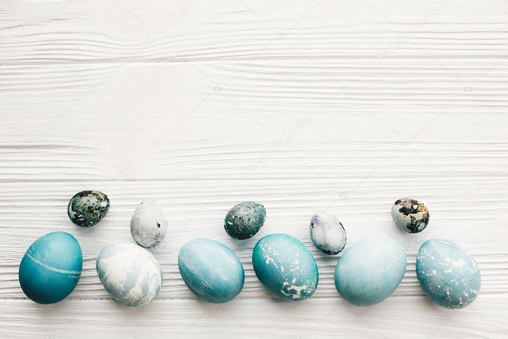 Stylish easter eggs on white wooden background with space for text, flat lay. Modern easter eggs painted with natural dye in blue marble color. Happy Easter, greeting card mockup