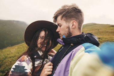 Selfie yapım ve güneşli Dağları üstünde gülümseyen mutlu hippi çift. Şık çift selfie fotoğraf çekme ve having fun aşık. Birlikte seyahat ve yolculuk tutkusu kavramı.