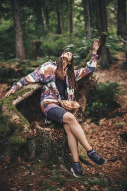 Şık hippi kız eğleniyor ve ormandaki dağlarda rahatlatıcı. Genç kadın gezgin Woods keşfetmek. Eko Tatil. Seyahat ve yolculuk tutkusu. Komik an