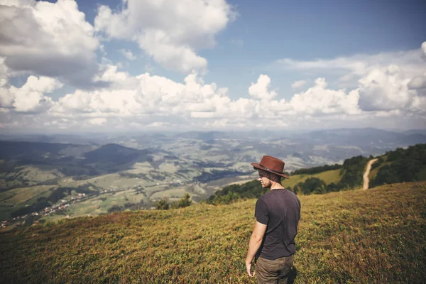 时尚的嬉皮士旅行者戴帽子站在山顶上的夏季山脉的背景 复制空间 旅行和流浪欲望的概念 — 图库照片