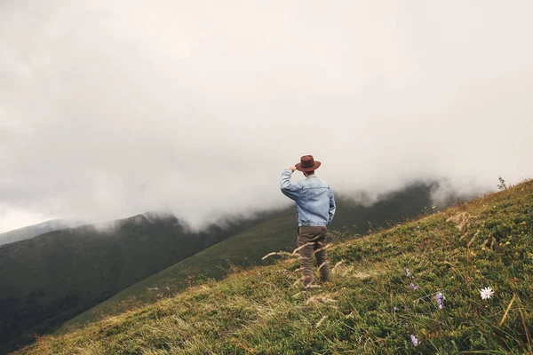 时尚的嬉皮士旅行者戴帽子站在山顶上雾蒙蒙的山上 复制空间 旅行和流浪欲望的概念 — 图库照片