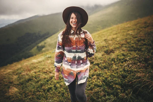 山脈の探索のバックパックを持つ幸せな若い女性の肖像画 帽子の山の上に笑顔でスタイリッシュな内気な少女 旅と放浪癖の概念 素晴らしい大気瞬間 — ストック写真
