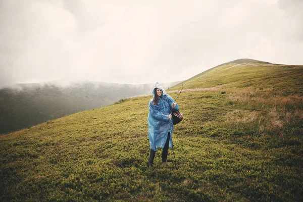 Stylish Hipster Girl Blue Raincoat Backpack Standing Top Misty Mountains — Stock Photo, Image