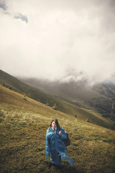 Stylish Hipster Girl Blue Raincoat Backpack Standing Top Misty Mountains — Stock Photo, Image