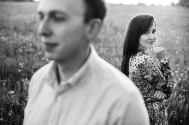 Bahar çayır güneş poz güzel genç bir çift. Çiçekli yeşil alanda kucaklayan mutlu şık aile. Romantik anlar. Bahar. Siyah ve beyaz fotoğraf