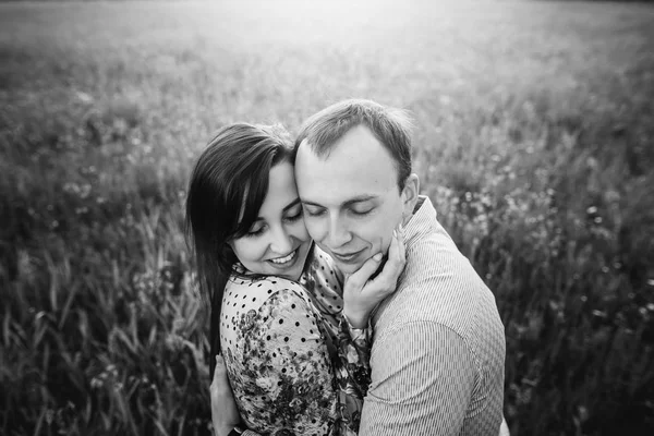 美しい若いカップル春の牧草地の日差しの中で優しく抱き締めます 花と緑のフィールドに抱きしめる幸せなスタイリッシュな家族 ロマンチックな瞬間 黒と白の写真 — ストック写真