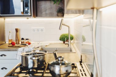 Çelik fırın, tencere, sebze, biber, baharat, Ahşap Masa üzeri yağlıboya ile ahşap kesme tahtası üzerinde bıçak ile modern mutfak yemek yemek. Ev yemeği. Gri renkli şık mutfak mobilya