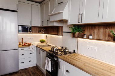 Şık mutfak iç tasarım. Lüks modern mutfak mobilya gri renk ve çelik fırın, buzdolabı, lavabo, ahşap masa, tencere. İskandinav tarzı gri dolaplarında. Ev yenileme.