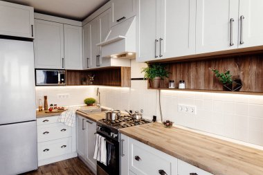 Şık mutfak iç tasarım. Lüks modern mutfak mobilya gri renk ve çelik fırın, buzdolabı, lavabo, ahşap masa, tencere. İskandinav tarzı gri dolaplarında. Ev yenileme.