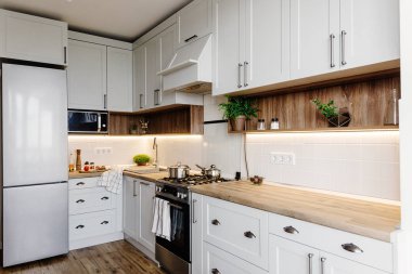Lüks modern mutfak mobilya gri renk ve çelik fırın, buzdolabı, lavabo, ahşap masa, tencere. İskandinav tarzı gri dolaplarında. Ev yenileme. Şık mutfak dekorasyon.