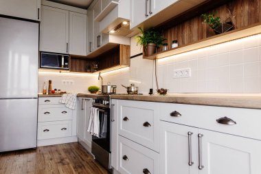Şık mutfak iç tasarım. Lüks modern mutfak mobilya gri renk ve çelik fırın, buzdolabı, lavabo, ahşap masa, tencere. İskandinav tarzı gri dolaplarında. Ev yenileme.
