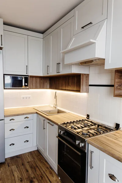 Lüks modern mutfak mobilya gri renk ve çelik fırın, buzdolabı, lavabo, ahşap masa üstü. İskandinav tarzı gri dolaplarında. Ev yenileme. Şık mutfak dekorasyon.