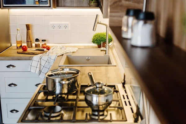 在现代厨房烹饪食物与钢烤箱 刀在木制切菜板与蔬菜 油在木桌面上 家庭食品 时尚的灰色厨房家具 — 图库照片