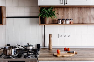 Çelik fırın, tencere, sebze, biber, baharat, Ahşap Masa üzeri yağlıboya ile ahşap kesme tahtası üzerinde bıçak ile modern mutfak yemek yemek. Ev yemeği. Gri renkli şık mutfak mobilya