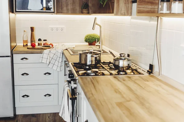 在现代厨房烹饪食物与钢烤箱 刀在木制切菜板与蔬菜 油在木桌面上 家庭食品 时尚的灰色厨房家具 — 图库照片