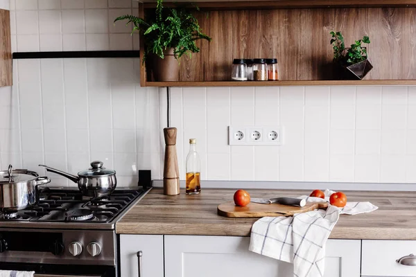 鋼のオーブン 唐辛子 スパイス 木製のテーブルの上の油と木製のまな板にナイフでモダンなキッチンで料理 家庭料理 グレー色のスタイリッシュなキッチン家具 — ストック写真