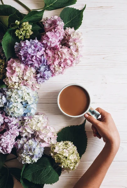 Hand Haltende Kaffeetasse Schönen Hortensienblüten Auf Rustikalem Weißem Holz Flach — Stockfoto