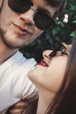 Şık hipster çift gülümseyen ve serin selfie yapma güneş gözlüğü. Mutlu aile çift kendi kendine portre yapmak ve yaz şehir akşam öpüşme aşık. Tatil ve seyahat birlikte
