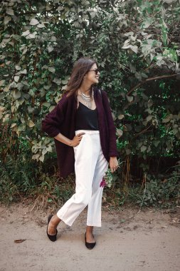 Mutlu boho kaygısız kız gülümseyerek ve yaz kırsal akşam yürüyüş kır çiçekleri buketi. Modern takı ve moda göz güneşli bahçede poz ile şık bohem kız