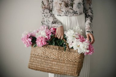 Boho kız pembe ve beyaz peonies rustik sepet içinde tutarak. Şakayık çiçekleri toplama bohem Çiçek elbiseli şık hipster kadın. Mutlu anneler günü. Uluslararası Kadınlar günü.