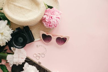 Şık kadınsı düz pembe peonies, şapka, fotoğraf makinesi, retro güneş gözlüğü, takı, çanta ve oje kopya alanı ile pastel pembe kağıt üzerine yatırın. Dünya Kadınlar günü. Merhaba bahar