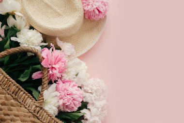 Hasır şapka ve beyaz ve pembe peonies pastel pembe kağıt üzerinde rustik çanta, düz yatıyordu. Bahar görüntü kopya alanı ile Merhaba. Yaz tatil kavramı. Dünya Kadınlar günü