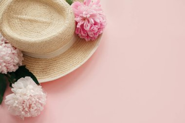 Hasır şapka ile beyaz ve pembe peonies pastel pembe kağıt üzerinde. Bahar görüntü kopya alanı ile Merhaba. Yaz tatil kavramı. Dünya Kadınlar günü. Mutlu anneler günü