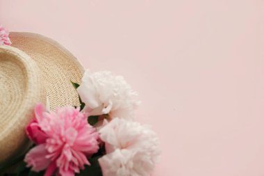 Beyaz ve pembe peonies pastel pembe kağıt, düz ile hasır şapka yatıyordu. Bahar görüntü kopya alanı ile Merhaba. Yaz tatil kavramı. Dünya Kadınlar günü. Mutlu anneler günü