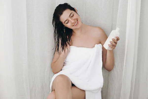 Jovem Mulher Feliz Toalha Branca Segurando Condicionador Para Cabelo Sorrindo — Fotografia de Stock