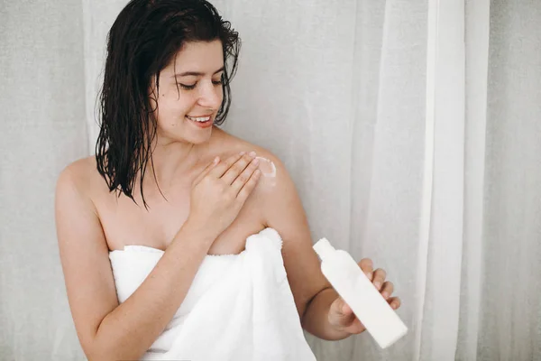 Joven Mujer Feliz Toalla Blanca Aplicando Crema Hidratante Hombro Baño — Foto de Stock