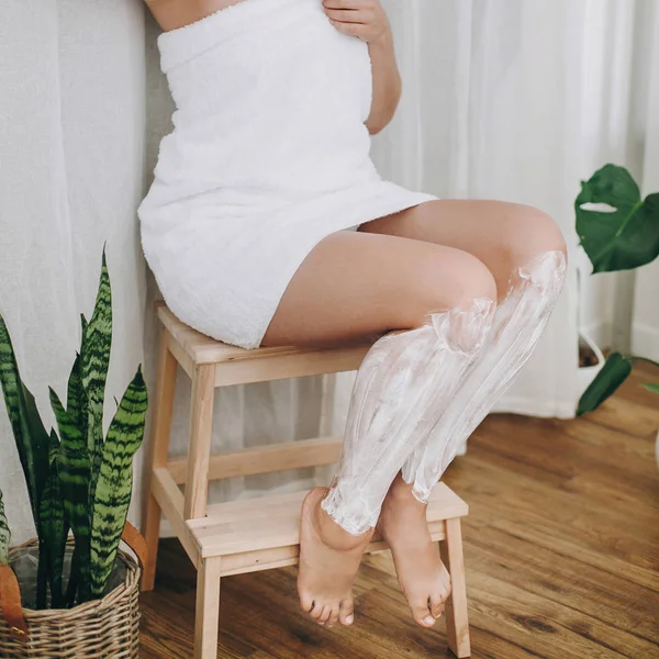 크림입니다 식물으로 욕실에서 그녀의 다리에 크림을 수건에 — 스톡 사진