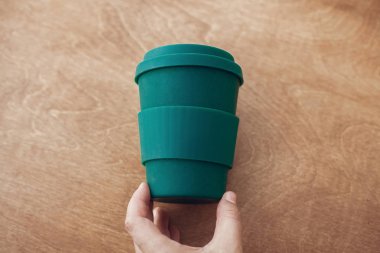 Eco kahve Kupası ahşap arka plan üzerinde tutan el. Kahve fincanı bambu fiber, sıfır atık kavramı. Tek Kişilik Kullanım plastik yasak. Kahve fincanını içinde götürün. Sürdürülebilir yaşam tarzı