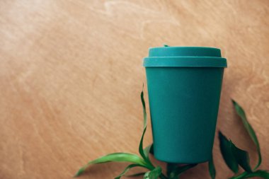 Şık yeniden kullanılabilir eco kahve Kupası ve bambu yaprakları ahşap arka planda, düz yatıyordu. Kupası doğal bambu fiber, sıfır atık kavramı. Tek Kişilik Kullanım plastik yasak. Kahve götürün