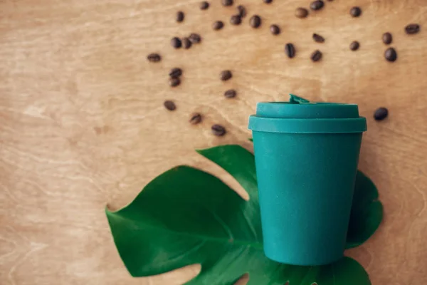 零浪费的概念 平坦的铺设 时尚可重复使用的生态咖啡杯在木制背景与烤咖啡豆和绿色的修道院叶 禁止一次性使用塑料 可持续发展的生活方式 — 图库照片