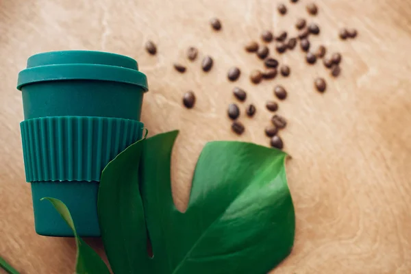 时尚可重复使用的生态咖啡杯在木制背景与烤咖啡豆和绿色的修道院叶 禁止一次性使用塑料 零浪费概念 可持续发展的生活方式 — 图库照片