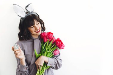 Paskalya yumurtası ve lale beyaz arka plan üzerinde kapalı, holding tavşan kulaklı metin için yer gülümseyen güzel kız. Paskalya avı kavramı, bahar mevsimlik selamlar.