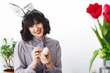 Boya ve fırça, lale vazo, metin için yer içinde tablo easter egg boyama tavşan kulakları güzel genç kadın. Mutlu Paskalya kavramı. Mutlu kız gülümseyerek ve Paskalya yumurtası dekorasyon