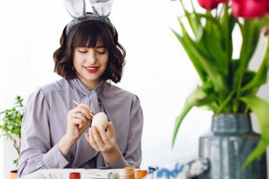 Boya ve fırça, lale vazo, metin için yer içinde tablo easter egg boyama tavşan kulakları güzel genç kadın. Mutlu Paskalya kavramı. Mutlu kız gülümseyerek ve Paskalya yumurtası dekorasyon
